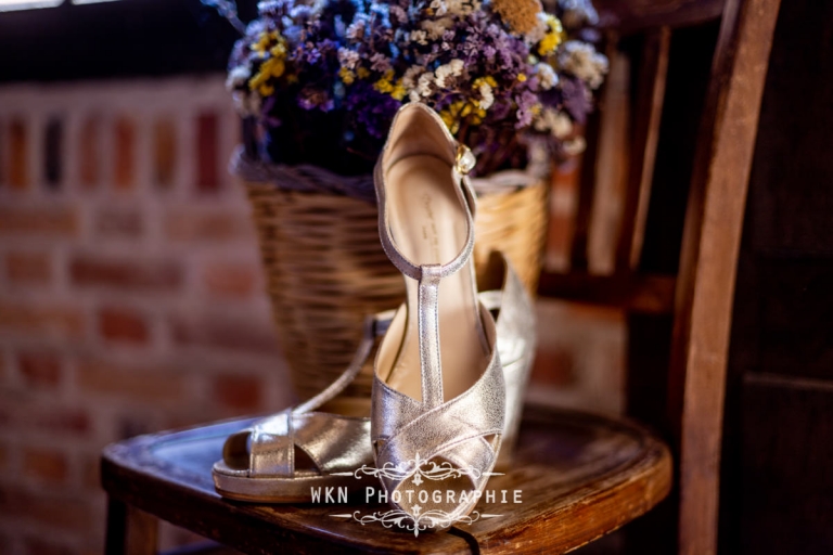 Les chaussures de mariée de Claire, soigneusement posées sur un sol élégant aux Écuries de Rivaulde.