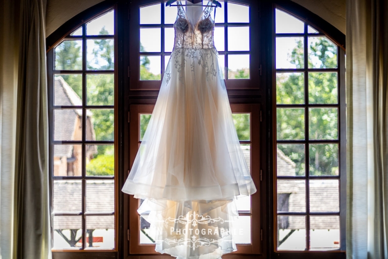 La robe de mariée de Claire suspendue aux Écuries de Rivaulde, baignée de lumière naturelle.